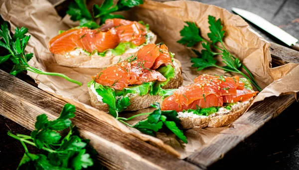 Salmon sandwich on a wooden tray. Against a dark background. High quality photo