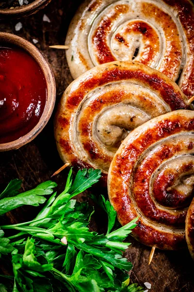 Grilled sausages with parsley and tomato sauce. Against a dark background. High quality photo