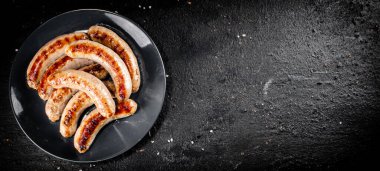 Ready grilled sausages on a plate. On a black background. High quality photo