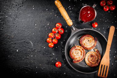 Delicious grilled sausages in a frying pan with fresh tomatoes. On a black background. High quality photo