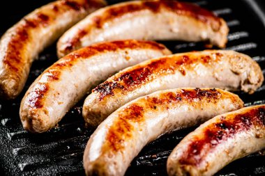 Grilled sausages in a frying pan. On a black background. High quality photo