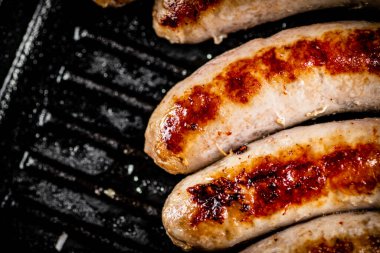 Grilled sausages in a frying pan. On a black background. High quality photo