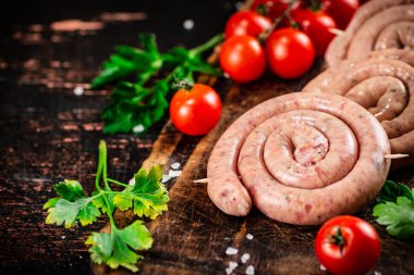 Round raw sausages with tomatoes and parsley. On a rustic background. High quality photo