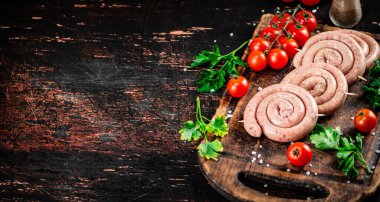Round raw sausages with tomatoes and parsley. On a rustic background. High quality photo