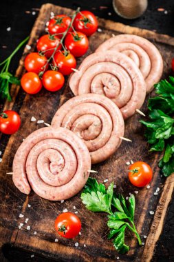 Round raw sausages with tomatoes and parsley. On a rustic background. High quality photo