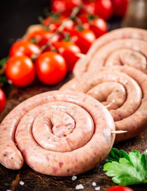 Round raw sausages with tomatoes and parsley. On a rustic background. High quality photo