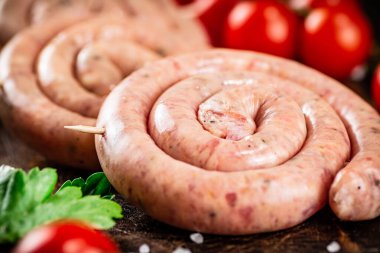 Round raw sausages with tomatoes and parsley. On a rustic background. High quality photo