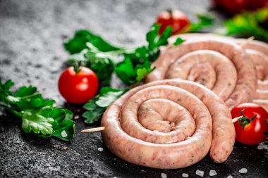 Round raw sausages with tomatoes and parsley. On a black background. High quality photo