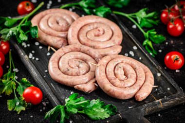 Raw sausages with parsley and tomatoes. On a black background. High quality photo