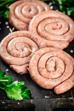Raw sausages with parsley. On a black background. High quality photo