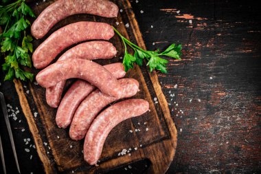 Raw sausages on a cutting board with parsley. On a rustic dark background. High quality photo