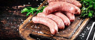 Raw sausages on a cutting board with parsley. On a rustic dark background. High quality photo