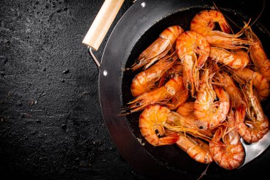 Saucepan with cooked boiled shrimp. On a black background. High quality photo