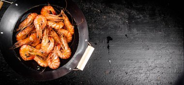 Saucepan with cooked boiled shrimp. On a black background. High quality photo