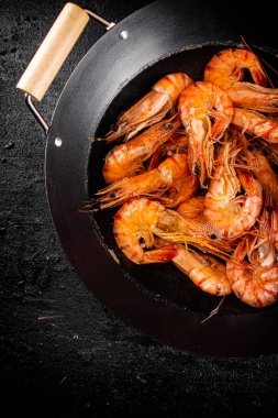 Saucepan with cooked boiled shrimp. On a black background. High quality photo