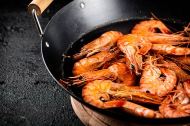 Saucepan with cooked boiled shrimp. On a black background. High quality photo