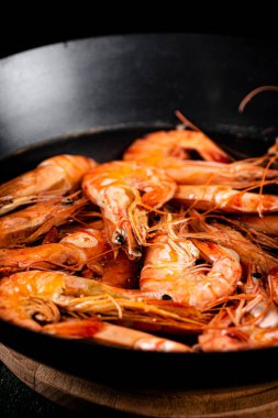 Saucepan with cooked boiled shrimp. On a black background. High quality photo