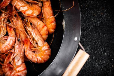 Saucepan with cooked boiled shrimp. On a black background. High quality photo