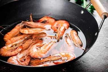 The shrimp are boiled in a pot of water. Against a dark background. High quality photo