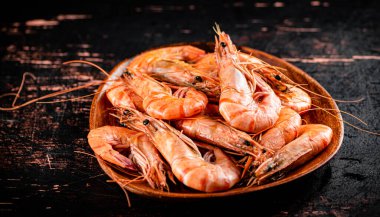 Boiled shrimp in a wooden plate. Against a dark background. High quality photo