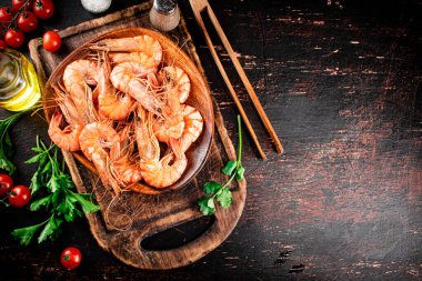 Boiled shrimp on a plate with tomatoes and parsley. Against a dark background. High quality photo