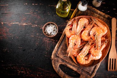 Boiled shrimp in a plate on a cutting board with spices. On a rustic dark background. High quality photo