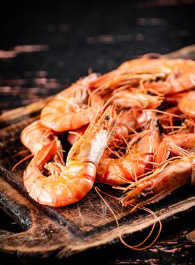 Cooked shrimp on a wooden cutting board. Against a dark background. High quality photo