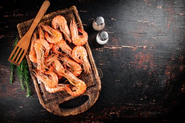 Cooked shrimp on a cutting board with spices and rosemary. Against a dark background. High quality photo