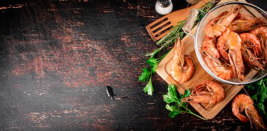 Boiled shrimp in a colander on a cutting board with parsley. Against a dark background. High quality photo