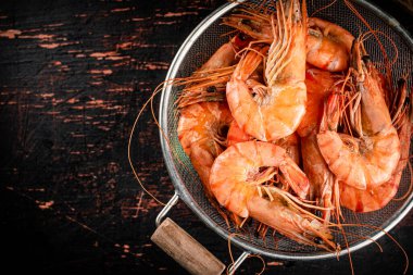 Fragrant boiled shrimp in a colander. On a rustic dark background. High quality photo