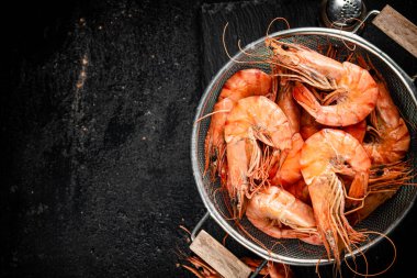 Fragrant boiled shrimp in a colander. On a rustic dark background. High quality photo