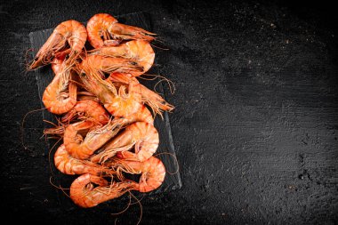 Delicious boiled shrimp on a stone board. On a black background. High quality photo