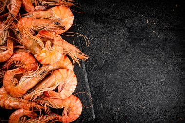 Delicious boiled shrimp on a stone board. On a black background. High quality photo
