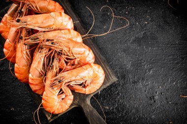 Boiled shrimp on a cutting board. On a black background. High quality photo