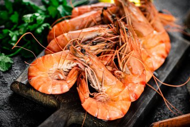 Boiled shrimp on a cutting board. On a black background. High quality photo