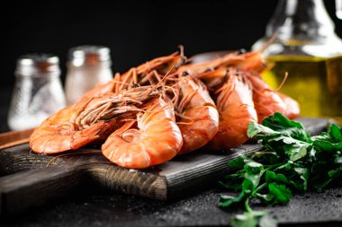 Boiled shrimp on a cutting board with parsley and spices. On a black background. High quality photo