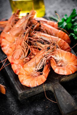 Boiled shrimp on a cutting board. On a black background. High quality photo