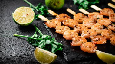 Grilled shrimp on a stone board with parsley and lime. On a black background. High quality photo