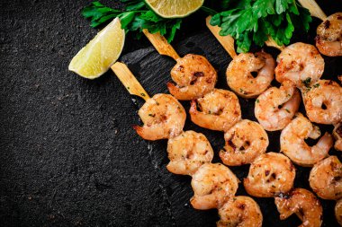 Grilled shrimp on a stone board with parsley and lime. On a black background. High quality photo