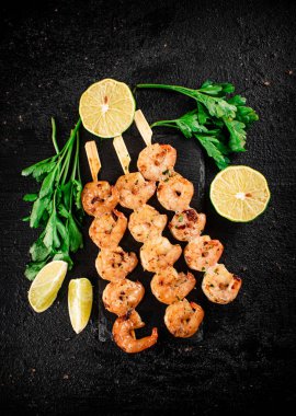 Grilled shrimp on a stone board with parsley and lime. On a black background. High quality photo