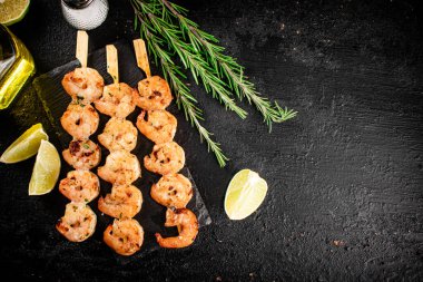 Grilled shrimp on a stone board with pieces of lime. On a black background. High quality photo