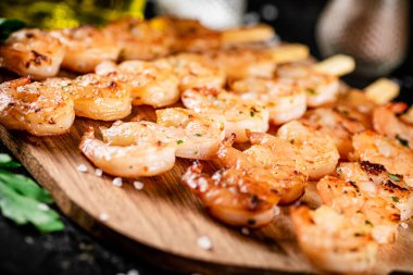 Grilled shrimp on a wooden cutting board. On a black background. High quality photo