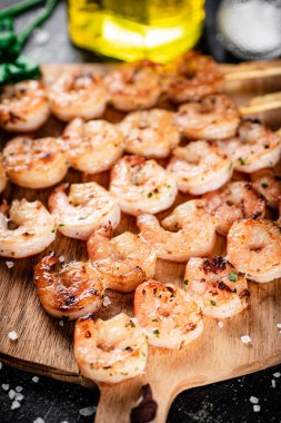 Grilled shrimp on a wooden cutting board. On a black background. High quality photo