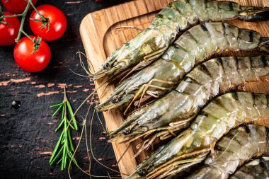 Raw shrimp with cherry tomatoes and rosemary. Against a dark background. High quality photo