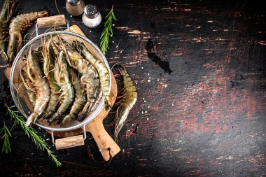 Fresh uncooked shrimp in a colander. On rustic dark background. High quality photo
