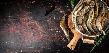 Fresh uncooked shrimp in a colander. On rustic dark background. High quality photo