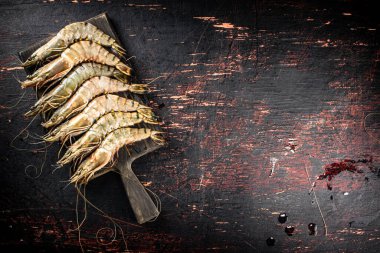 Raw shrimp on a wooden cutting board. On a rustic dark background. High quality photo