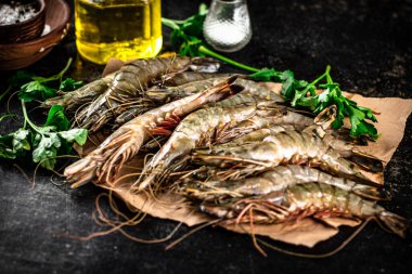 Raw shrimp on paper with spices and parsley. On a black background. High quality photo