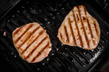 Tuna steak in a grill pan. On a black background. High quality photo