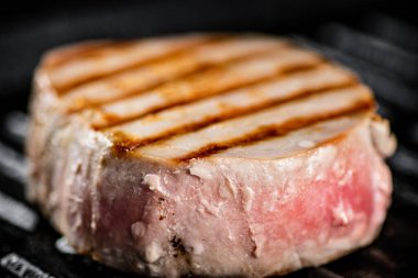 Tuna steak in a grill pan. On a black background. High quality photo